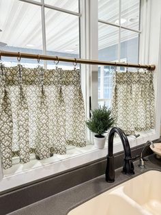 a kitchen sink with a faucet next to a window covered in green and white curtains