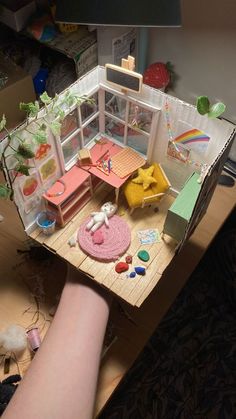 a doll house with furniture and accessories on the floor in front of a woman's leg