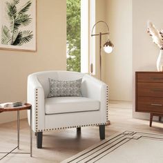 a living room with a white chair and two end tables in front of a window