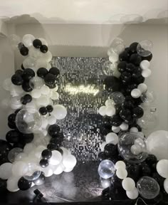 an arrangement of black and white balloons in a room with silver sequins on the floor