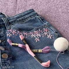 a pair of jeans with pink flowers on them and a hair dryer in the back pocket