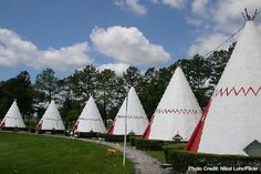 several white teepee houses with red trim on them