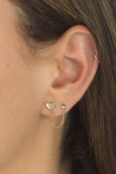 a close up of a woman's ear with two heart shaped earrings on it