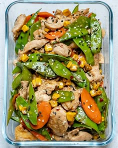 a glass casserole dish filled with chicken, peppers, corn and carrots