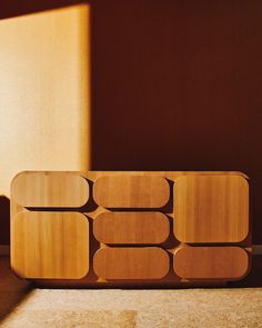 a wooden shelf sitting on top of a floor next to a wall with a window