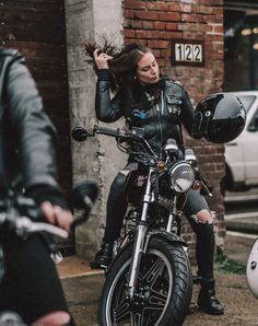 a woman sitting on top of a motorcycle next to a man in black leathers