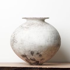 a white vase sitting on top of a wooden table