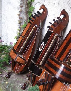 three wooden musical instruments sitting next to each other on a stone floor in front of a white wall