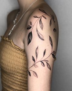 a woman's arm with black leaves on the left side of her body,