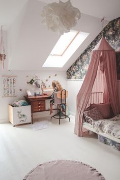 a bedroom with a bed, desk and chair in it's corner under a slanted skylight