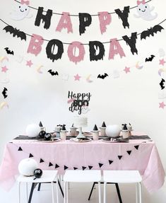 a birthday party with pink and black decorations on the table, bats hanging from the ceiling