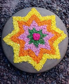 a rock with flowers painted on it sitting in the middle of some grass and gravel