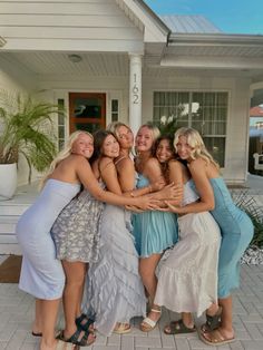 a group of women standing next to each other in front of a house