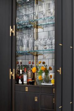 a bar with lots of bottles and glasses on it's glass shelves in the corner