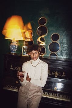 a man sitting at a piano holding a drink