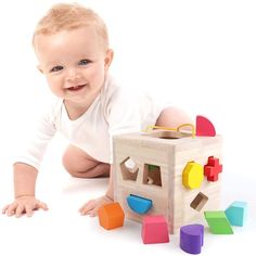 a baby is laying on the floor next to a wooden block and building blocks set