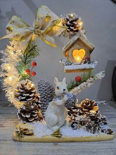 a white rabbit sitting in front of a christmas wreath with pine cones and other decorations