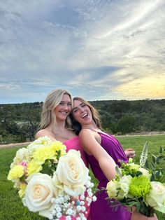 two women in purple dresses holding bouquets of white and yellow flowers on the grass