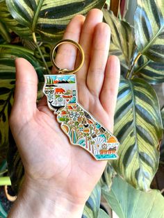 a person holding a keychain with a map of the state of california on it