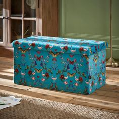 a large blue box sitting on top of a wooden floor in front of a window