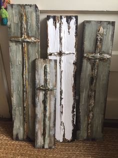 three pieces of wood that have been painted white and grey with crosses on the sides