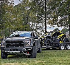 a large truck with two atvs on it's bed is parked in the grass