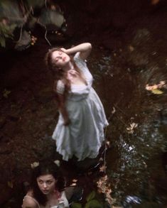 two women are standing in the water and one is holding her head up to her chest