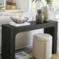 a living room with a couch, table and two vases on the coffee table