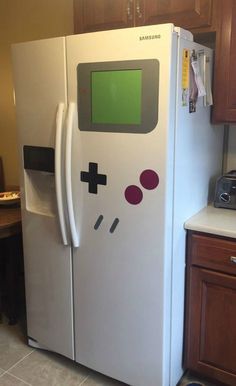 a white refrigerator with a game controller on it's door and some brown cabinets