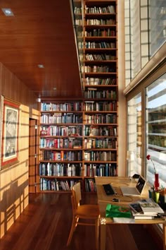 a room filled with lots of books on top of a wooden floor next to a window