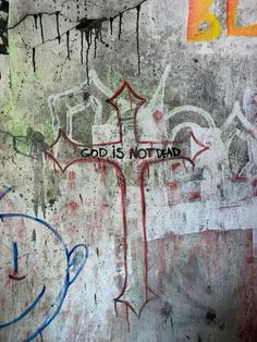 graffiti on the side of a wall that says god is not dead with a crucifix