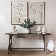 two vases with flowers are sitting on a table in front of some framed pictures