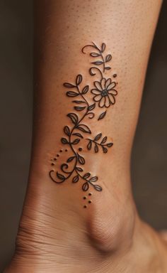 a woman's foot with a flower tattoo on the side of her leg,