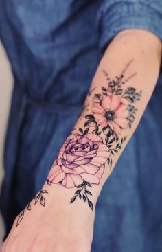 a woman's arm with flowers and leaves on the left side of her wrist