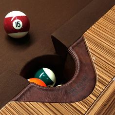 two pool balls are sitting in the corner of a pool table with a brown leather cover