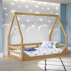 a child's bed with a wooden frame and canopy, against a blue wall