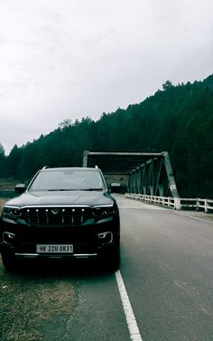 a black car driving down a road next to a bridge