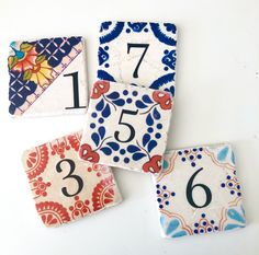 four colorful tiles with numbers on them sitting next to each other in front of a white background