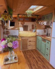 the interior of a tiny home with wood flooring and green cabinets, including a bed