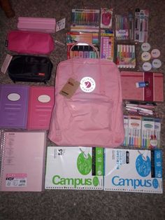 the contents of a pink backpack are laid out on the floor next to school supplies