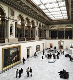 people are standing in the middle of a large room with many paintings on the walls