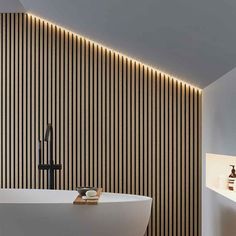 a white bath tub sitting next to a bathroom sink under a light on the wall