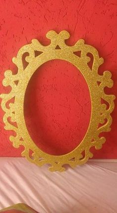 a gold frame sitting on top of a bed next to a red wall in a room