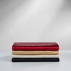 three different colored sheets stacked on top of each other in front of a white wall