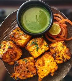 a plate with tofu, carrots, and green sauce on it next to some sliced onions