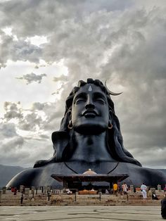 a large buddha statue sitting in front of a cloudy sky