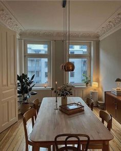 a dining room table and chairs in front of two windows