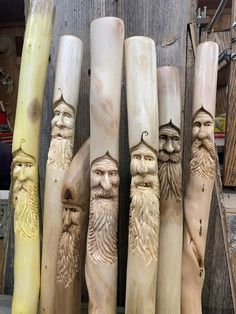 five carved wooden poles with faces and beards