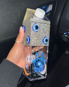 a person is holding a box with eyes on it in their hand and the inside of her car