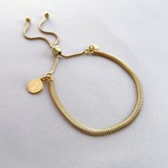 "Put your stamp on our gorgeous yellow gold vermeil snake bracelet and stack them up for a statement look!  Our yellow gold mini disc charm measures 8x8mm, perfectly sized for initials. The yellow gold disc sits on a sterling silver snake slider bracelet, which can be adjusted from 4.5\" to 9.5\" to fit most adult wrists perfectly.  Our yellow gold vermeil jewellery is made with genuine .925 sterling silver which has been expertly plated with a yellow gold layer.  Presented on your choice of bea Adjustable Gold Snake Chain Bracelet, Adjustable Tarnish Resistant Gold Snake Chain Bracelet, Adjustable Snake Chain Gold Bracelet For Everyday, Gold Round Minimalist Charm Bracelet, Minimalist Adjustable Yellow Gold Charm Bracelet, Adjustable Minimalist Yellow Gold Charm Bracelet, Gold Engraved Minimalist Charm Bracelet, Adjustable Yellow Gold Snake Chain Bracelet, Modern Adjustable Gold Name Bracelet